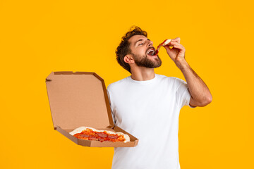 man holding delivery box and enjoying slice of pizza, studio