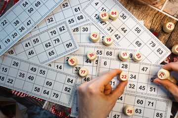 Playing lotto game. Person holding cube with figure on bingo card background. Nostalgia lifestyle....