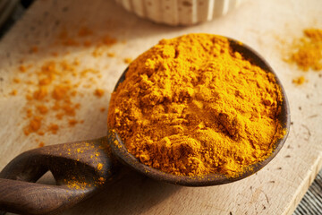 Turmeric root powder on a spoon on a wooden table