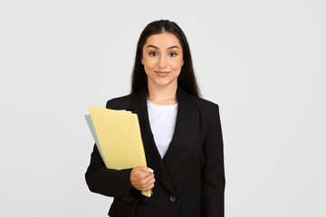 Confident young businesswoman with folders