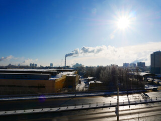View of a winter city with a smoking chimney.