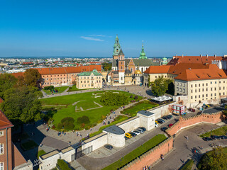 Royal Wawel Gothic Cathedral in Krakow, Poland, with Renaissance Sigismund Chapel with golden dome, walking people and lawn with foundations of an old destroyed building and two churches. Aerial view - 735352228