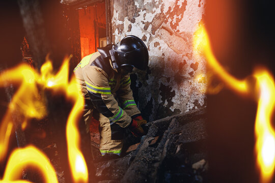 Fireman in burning wooden house clears rubble to save people and extinguish fire. Concept rescue services at work