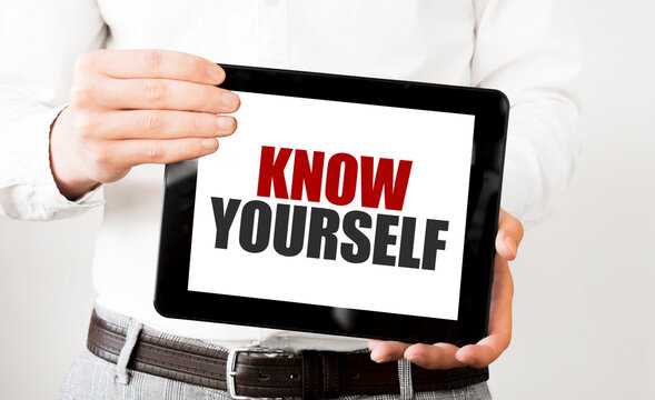 Text KNOW YOURSELF on tablet display in businessman hands on the white background. Business concept