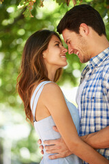Obraz premium Couple, smile and happy in nature for love, bonding and connection with trees in sunshine in Canada. Man, woman and date with romantic embrace for admiration, care and hug in park on Valentines Day