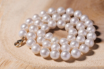 beautiful women's necklace made of natural white sea pearls on a wooden backing