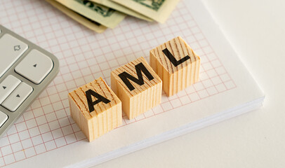 Wooden blocks with AML letters on notebook and money. Concept of Anti-Money Laundering in finance.