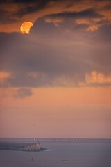 The moon hides between the clouds over the wind turbines of the port of Bilbao