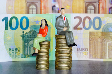 Figures of male and female people on different piles of money coins, concept of income inequality