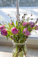 Purple bouquet of tulips near a large window overlooking the winter garden