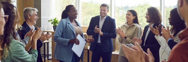 Group of happy diverse business people applauding to female speaker standing in a circle in meeting room. Successful company employees clapping a colleague on business training or conference. Banner. - obrazy, fototapety, plakaty