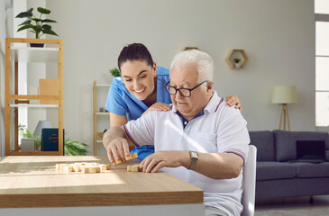 Development of senior people skills. Friendly, caring nurse helps elderly man correctly combine and...