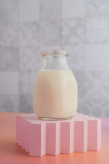 Bottle of milk on pink geometic cup holder and grey tile background