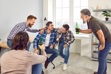 Group of happy male friends drinking beer at home. Laughing men celebrating meeting, drinking beer...