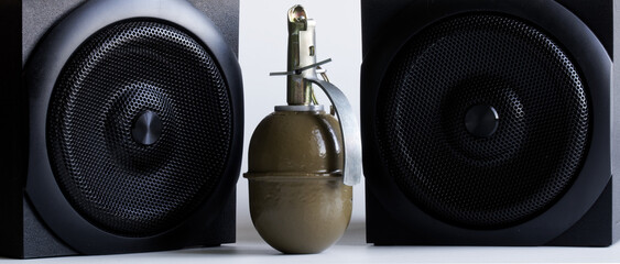 Hand grenade and two black audio speakers. A metaphor for powerful sound or explosive audio and...