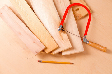 Hand jigsaw, wood and clamps are on the table.