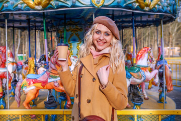 Obraz na płótnie Canvas Girl with a can of coffee in the background of the Carousel