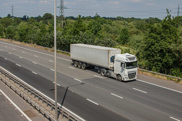 White lorry with shipping container in motion on the motorway.