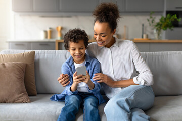 Excited black boy with mother exploring smartphone together