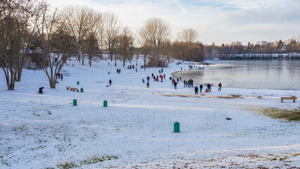 Winter tumult with sleds on a snowy slope by frozen lake on a day off
