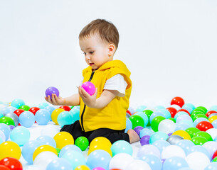 Fototapeta na wymiar Little boy plays in pool of balls.