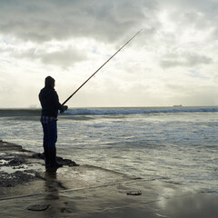 Casting, fishing rod and man at a beach for water hobby, recreation or stress relief in nature....