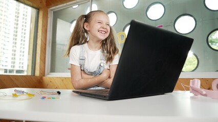 Cute girl using laptop programing software while looking and laughing at camera. Pretty child...
