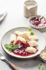 Lazy dumplings, vareniki with raspberry jam decorated with almond petals and mint leaves close up. Boiled cottage cheese homemade gnocchi