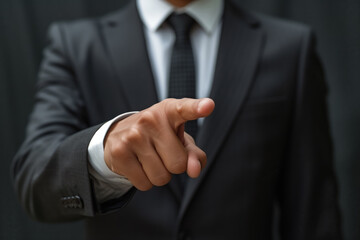 Fototapeta premium A male businessman in a business suit points his finger in the direction on a grey background