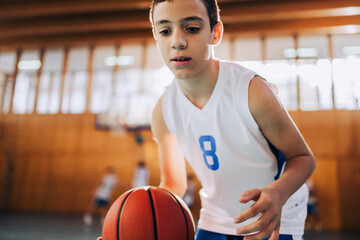Portrait of a basketball kid catching a ball on court during training.