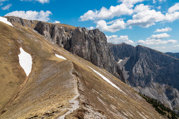 Idyllic hiking trail along golden alpine meadow with panoramic view of majestic Hochschwab massif,...