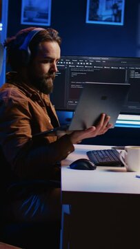 Engineer typing code in apartment office, using javascript programming language to develop software application. It admin using multimonitor desktop setup and notebook to finish tasks, camera B