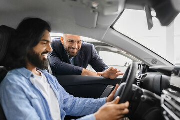 Happy eastern man sitting in car listening to sales manager