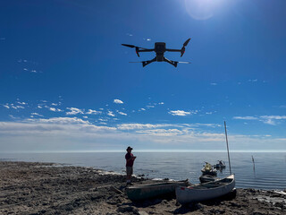 A Man Flying his UAV Drone at Bombay Beach, California, from the makeshift Dock Area with the Sun Behind.