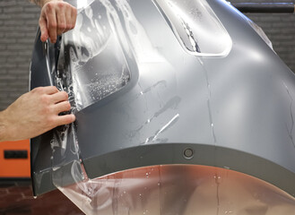 Close up of paint protection film installation on front bumper of modern luxury car. PPF is...