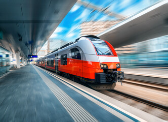 High speed train in motion on the train station at sunset in Vienna, Austria. Red modern intercity passenger train with motion blur effect. Railway platform. Railroad. Commercial transportation - obrazy, fototapety, plakaty