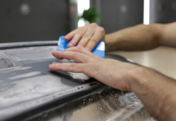 Close up of paint protection film installation on front bumper of modern luxury car. PPF is...