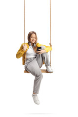 Female teenager sitting on a swing and looking at a smartphone