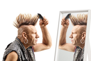 Man combing his mohawk hairstyle with a brush in front of a mirror - obrazy, fototapety, plakaty