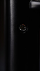 A tightly focused photograph highlights a screw positioned on the rear side of a battery charger,...