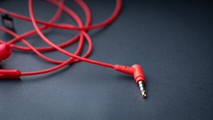 Red earphones are elegantly displayed against a sleek black background, with ample space available for text. The bold red color of the earphones contrasts beautifully with the dark backdrop, creating 