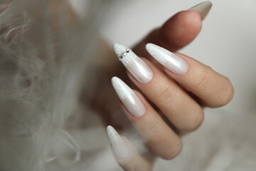 Pearl rubbing with a design of rhinestones on long nails.