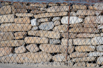 Picture of a gabion made of stone and iron. Gabions can flex to ground movement, dissipate energy from flowing water, and drain freely