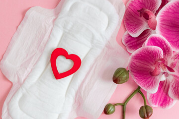Women's sanitary pad with red heart and orchid on a pink background. © Nataliya