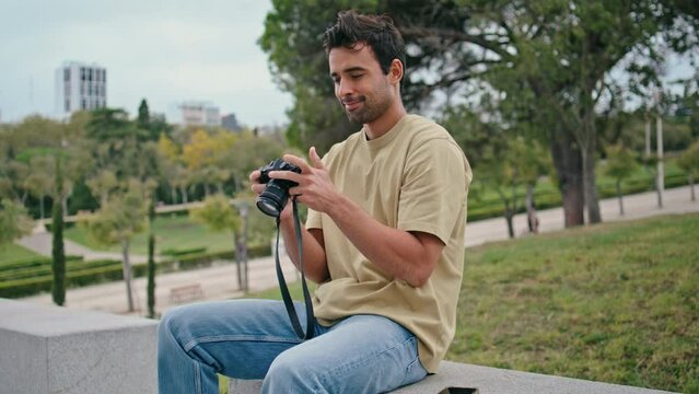 Man looking professional camera at summer urban weekend. Happy hispanic tourist
