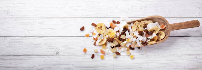 Exotic mix of dehydrated fruits in scoop on white wooden background, top view, space for text.