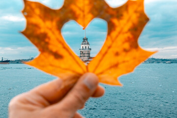 Photo of the Maiden's Tower on the Bosphorus. The man took a photo of the Tower with an autumn leaf...