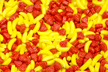 Top view flat lay background of Colorful sweet bright candy pieces shaped like yellow bananas and red strawberries.