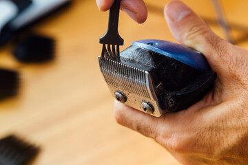 Barber cleaning his clipper. Close up view. Maintenance of work tool.