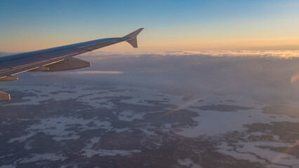 Obraz premium Snowy winter orange sunset landscape in Finnish Lapland view from an airplane window